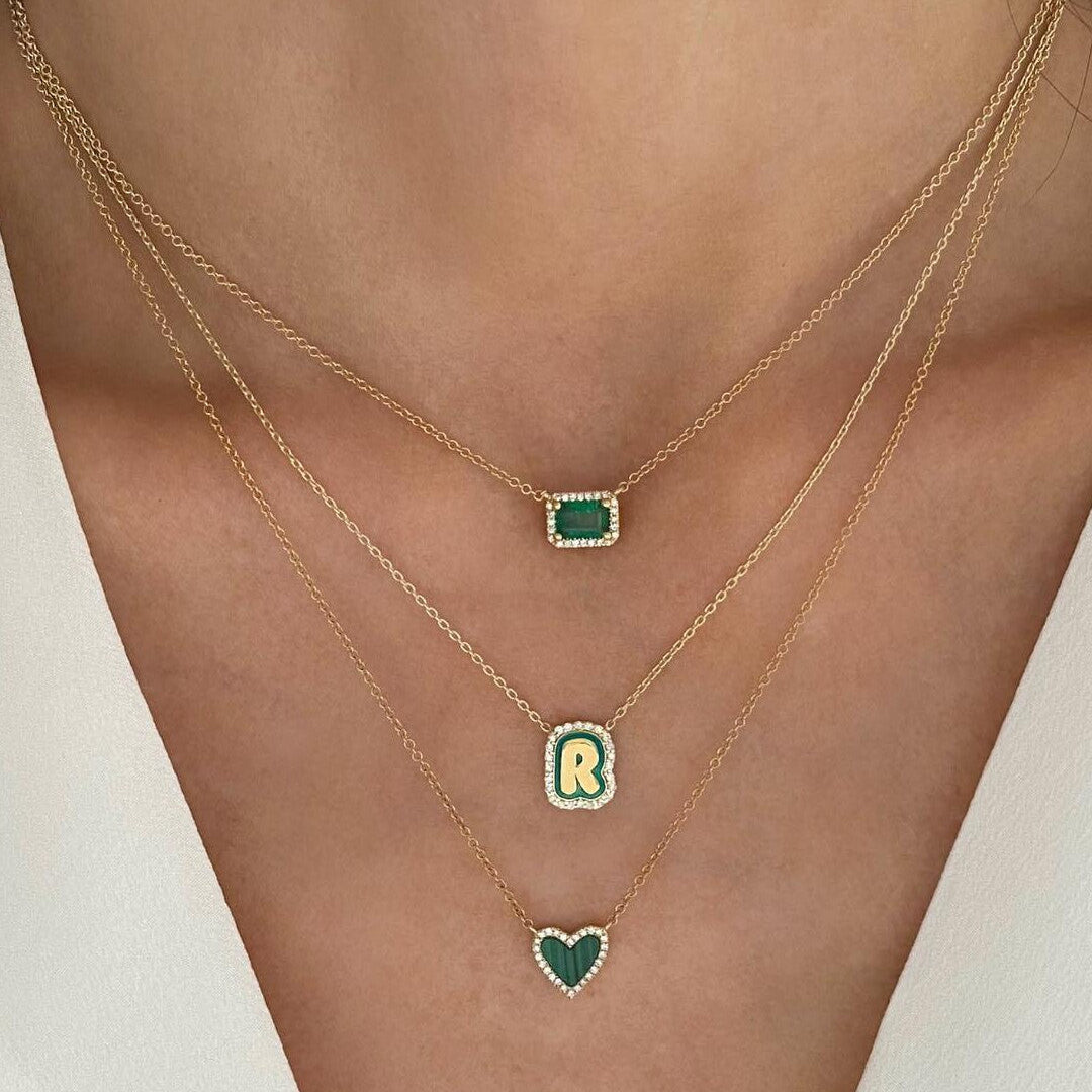 Necklace with green gemstone pendants on a person wearing a white top