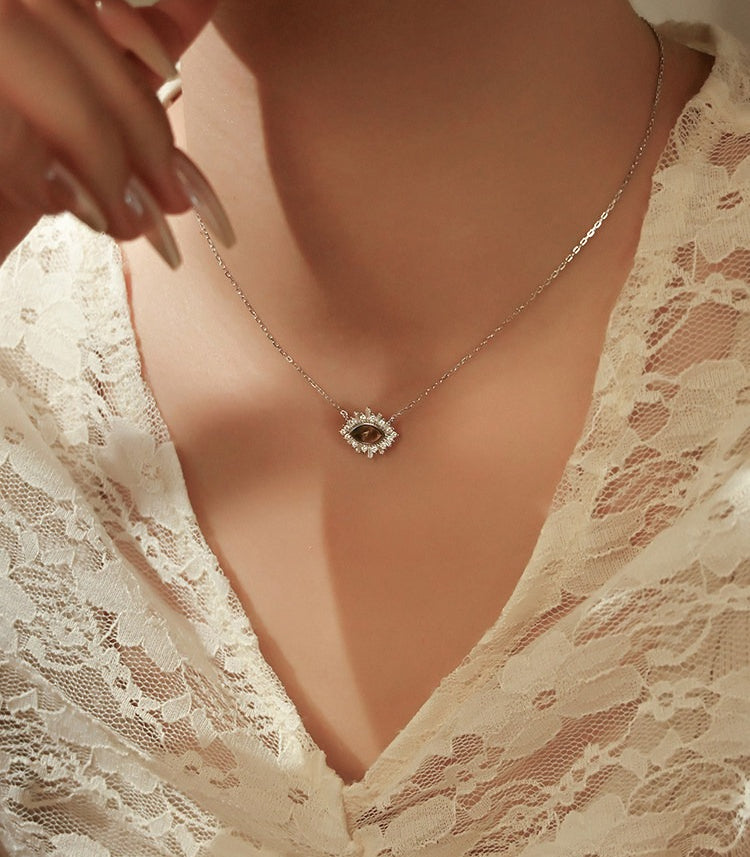 Necklace with a diamond pendant worn by a person in a lace garment.