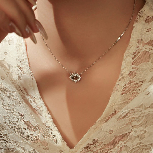 Necklace with a diamond pendant worn by a person in a lace garment.