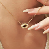 Gold necklace with a pendant held by a hand against a neutral background