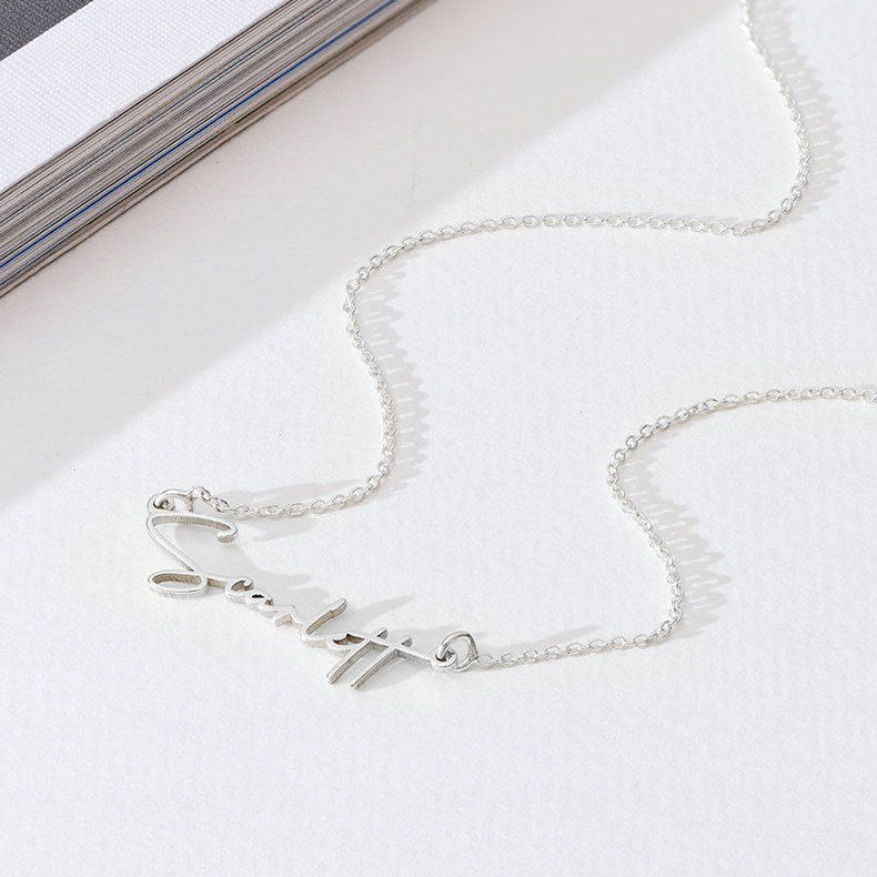 Silver necklace on a white surface with a magazine in the background