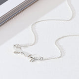 Silver necklace on a white surface with a magazine in the background