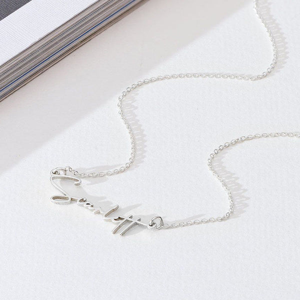 Silver necklace on a white surface with a magazine in the background