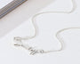 Silver necklace on a white surface with a magazine in the background