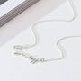 Silver necklace on a white surface with a magazine in the background