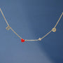 Gold necklace with a red heart pendant on a blue background